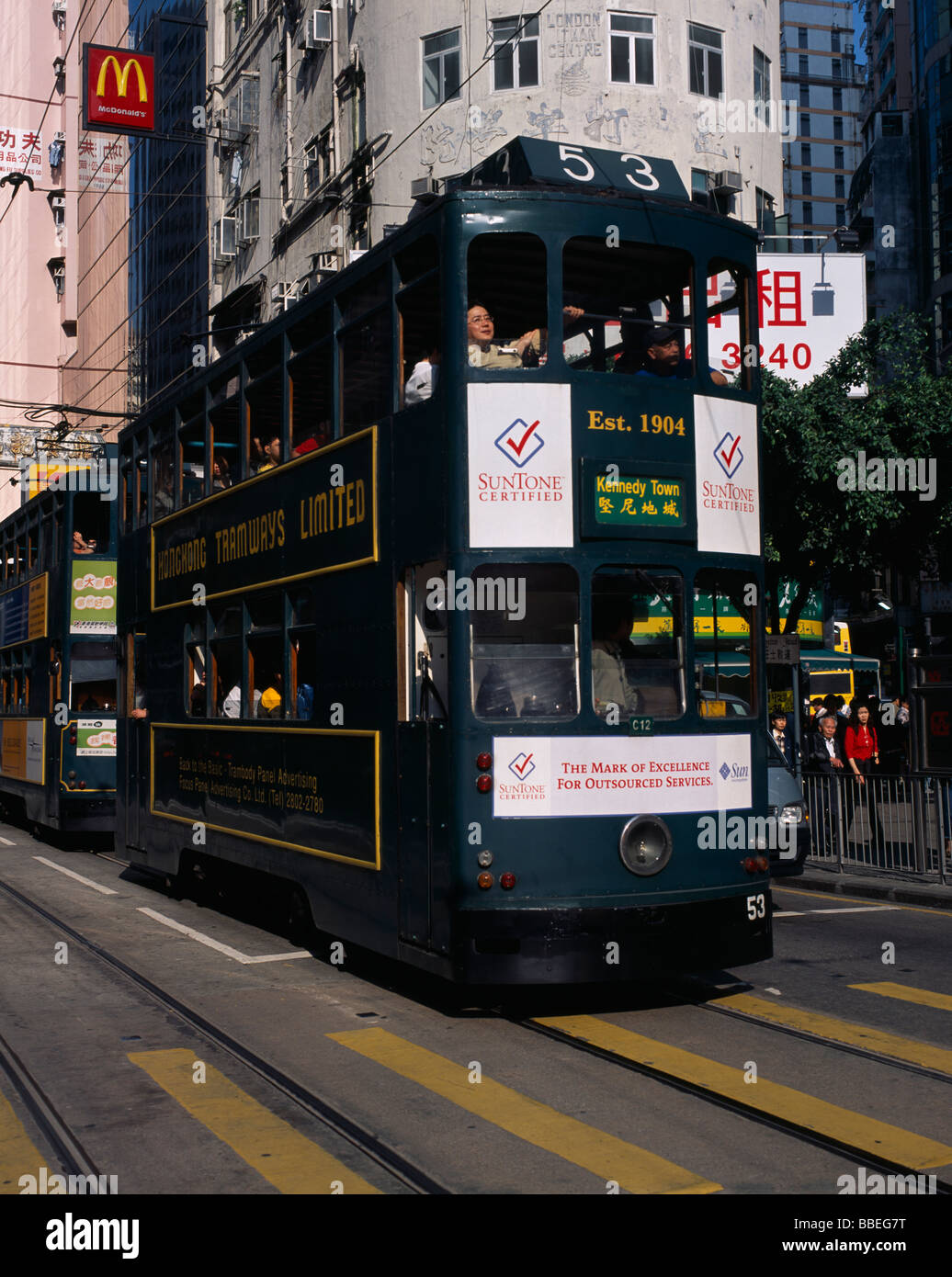 CHINA Hong Kong Island tram on city street with high rise buildings and advertising hoardings. Sign for McDonalds above tramline Stock Photo