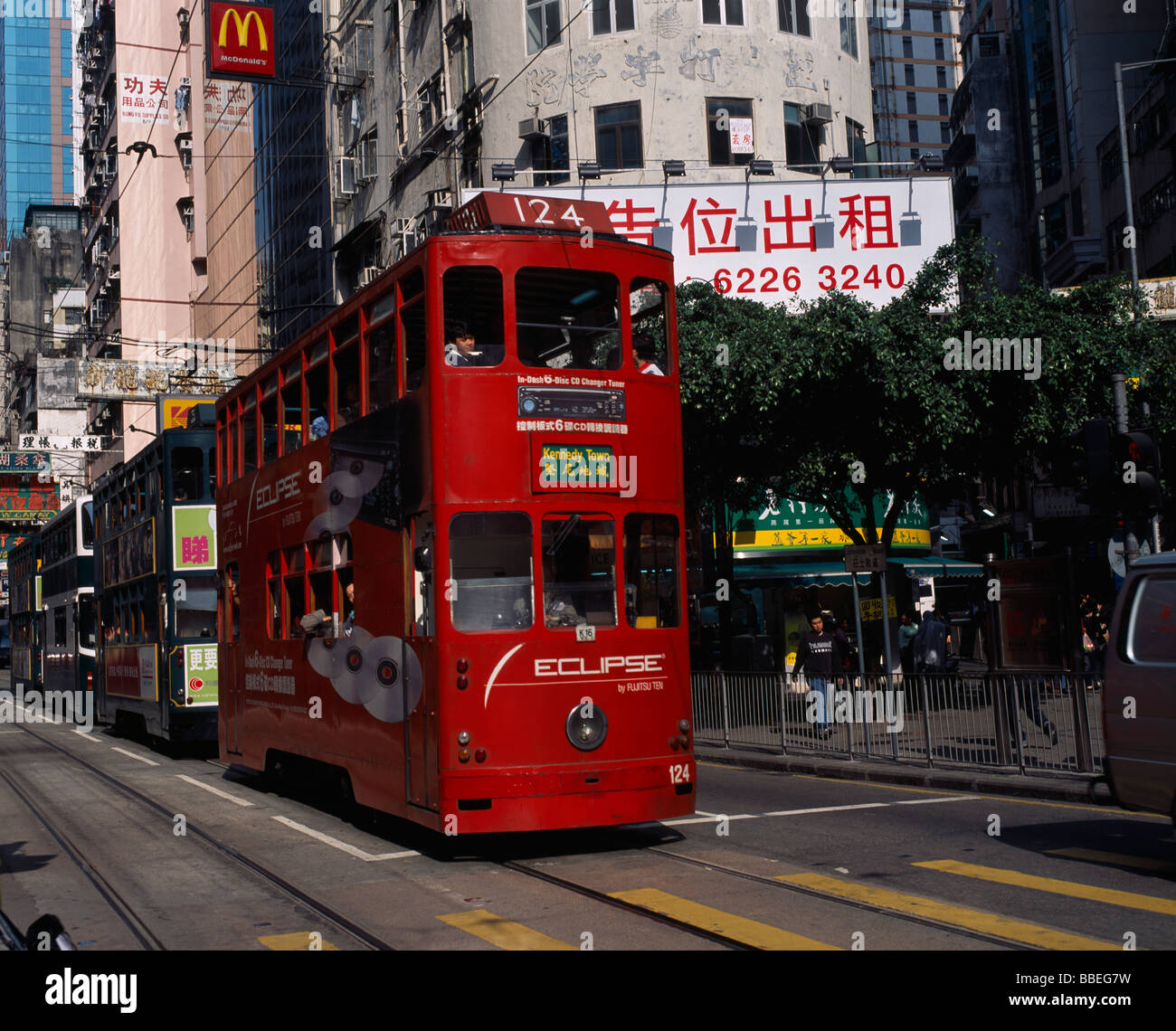 CHINA Hong Kong Island trams on city street with high rise buildings and advertising hoardings and McDonalds sign overhead. Stock Photo