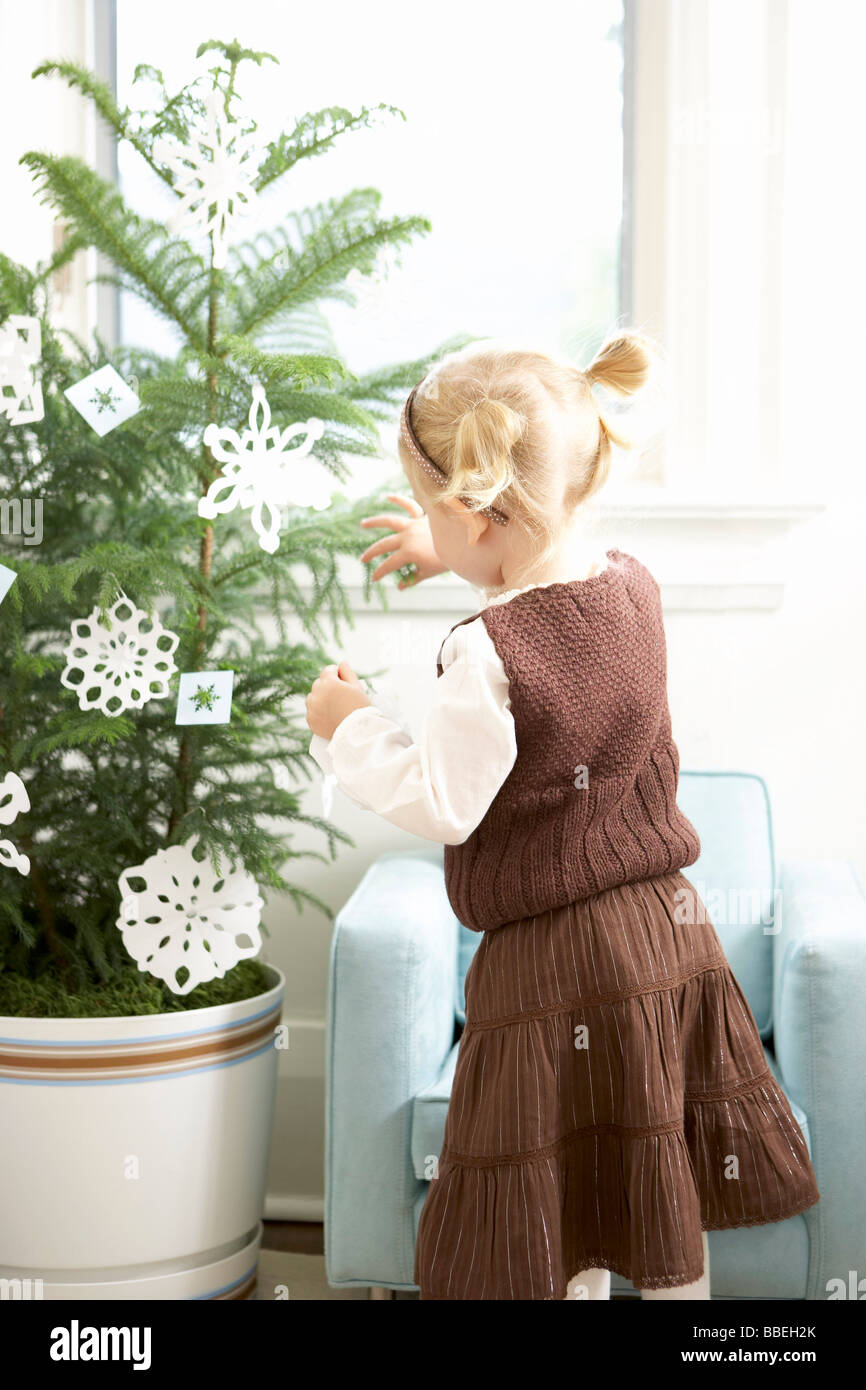 Little Girl Decorating a Christmas Tree With Paper Snowflakes Stock Photo