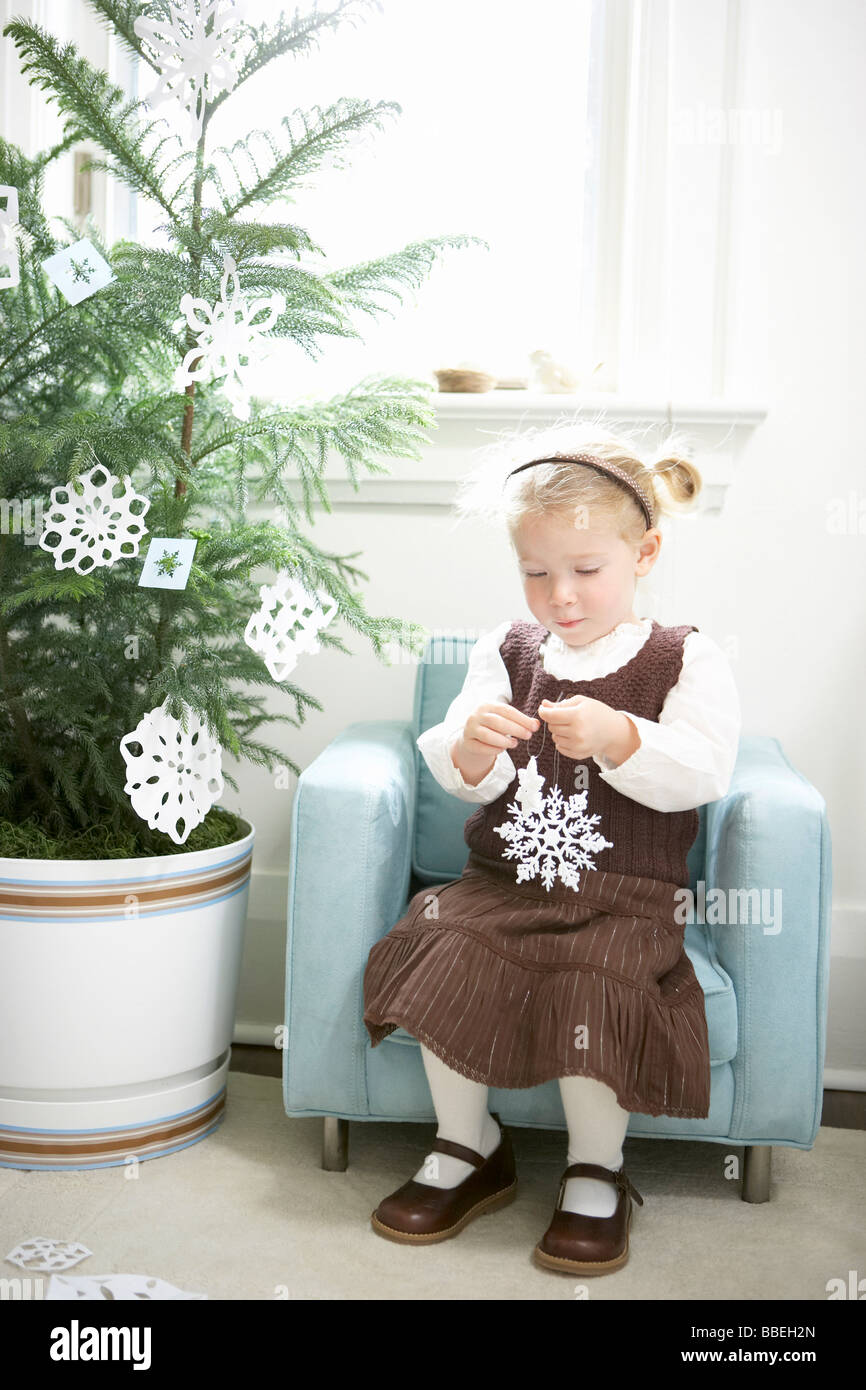 Little Girl Decorating a Christmas Tree With Paper Snowflakes Stock Photo