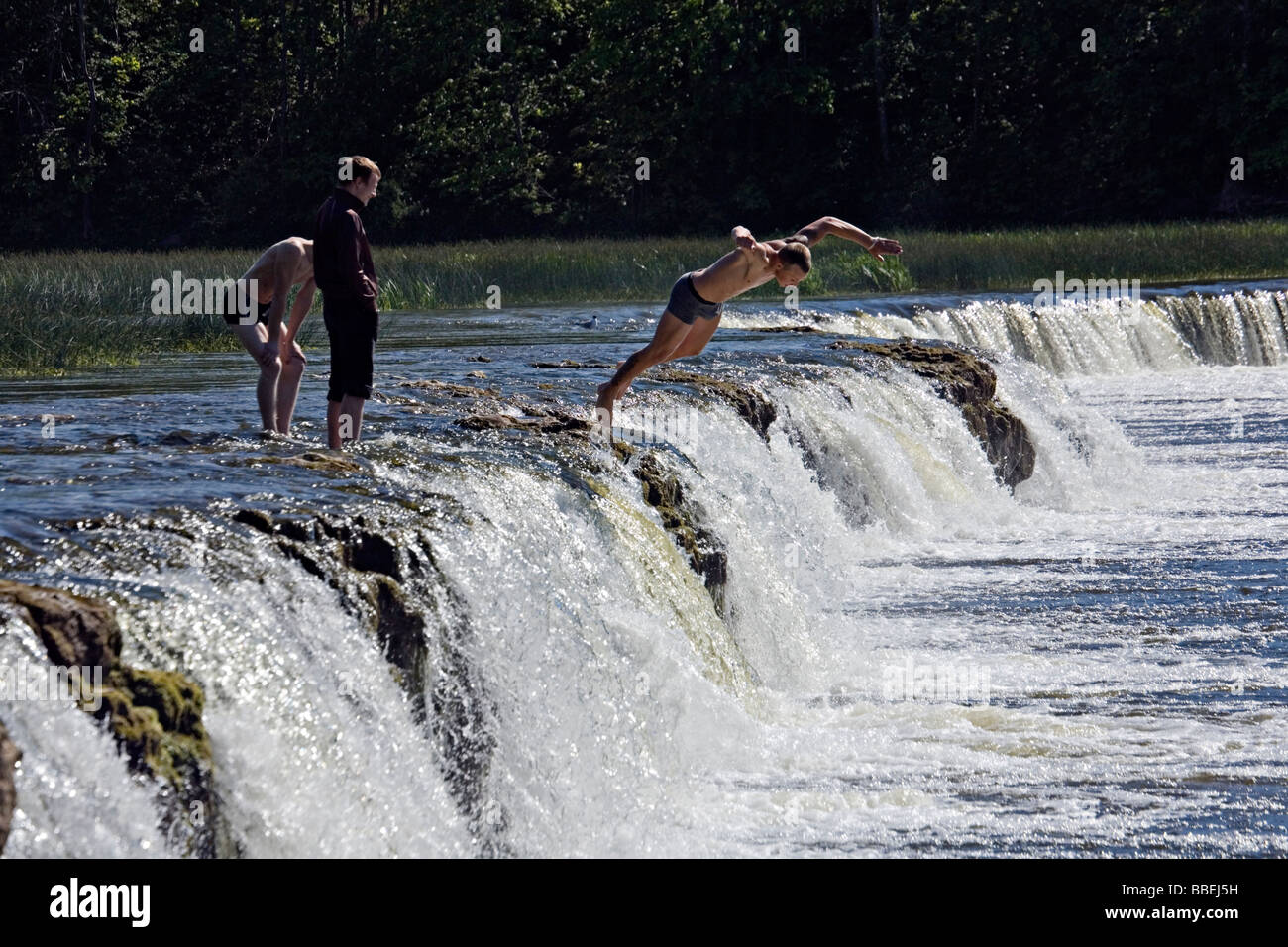 Boys jumping into Ventas Rumba waterfalls in Kuldiga city Kurzeme Latvia Stock Photo