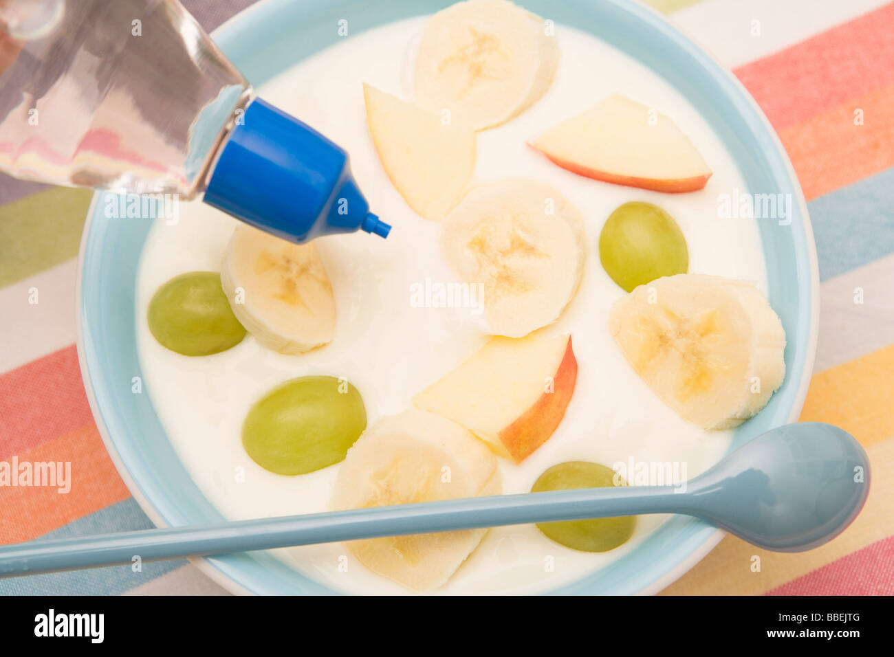 Putting Artifical Sweetener in Bowl of Fruit and Yogurt Stock Photo