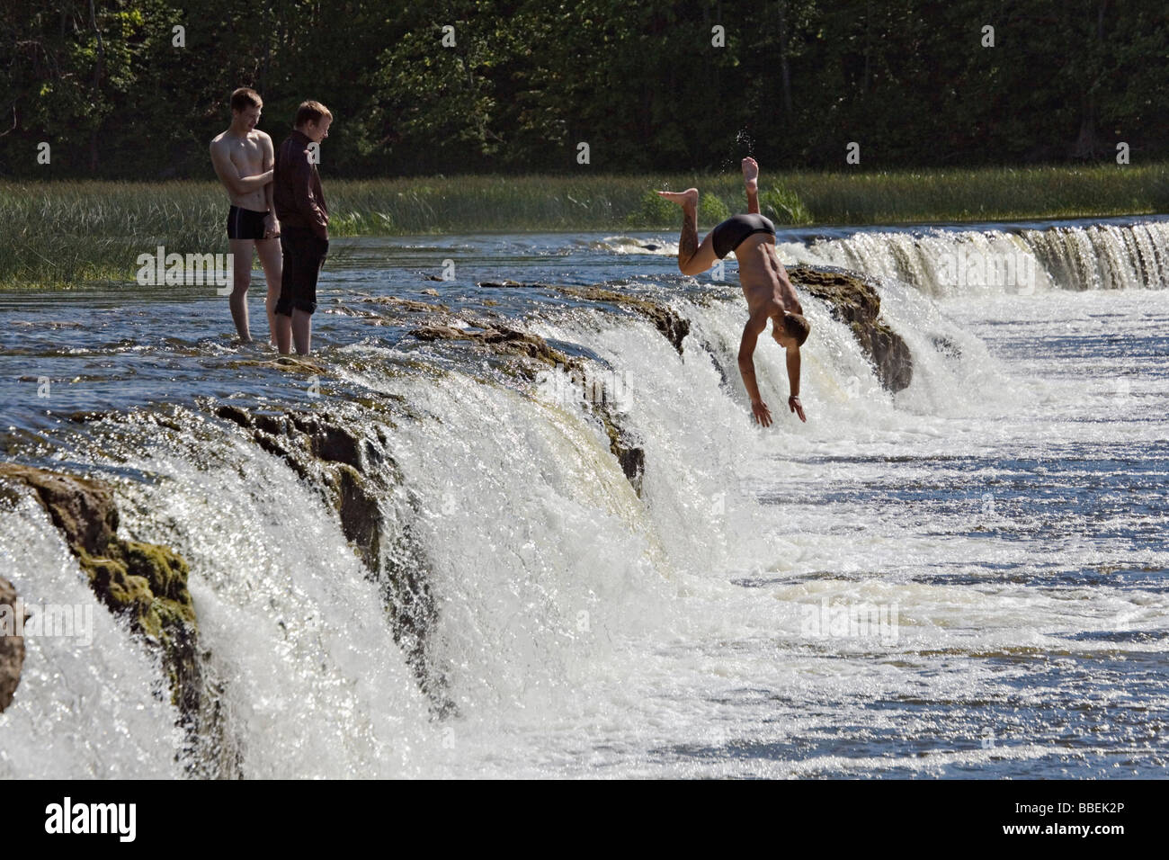 Boys jumping into Ventas Rumba waterfalls in Kuldiga city Kurzeme Latvia Stock Photo