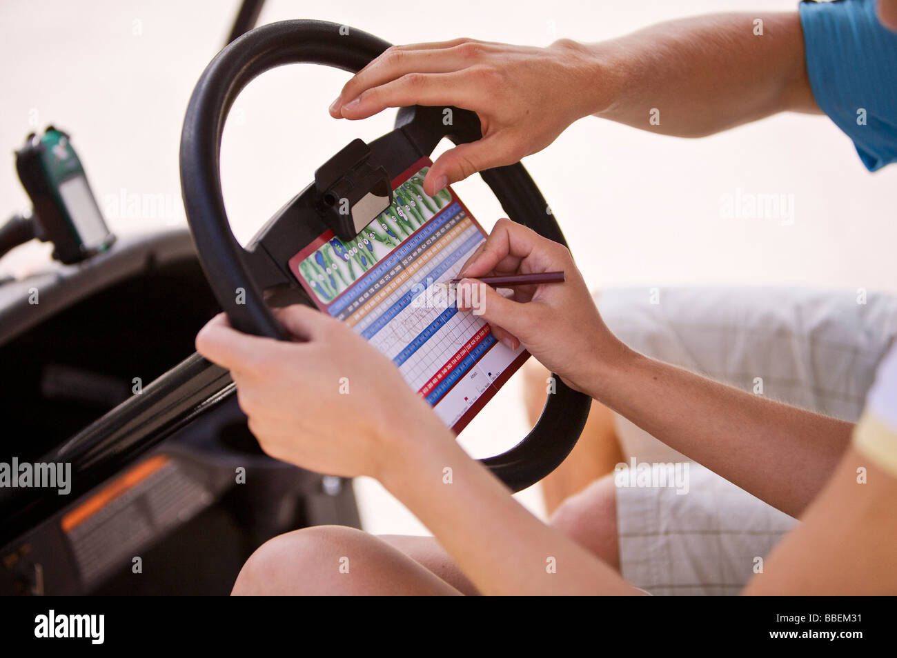 Couple Marking Score Card in Golf Cart Stock Photo