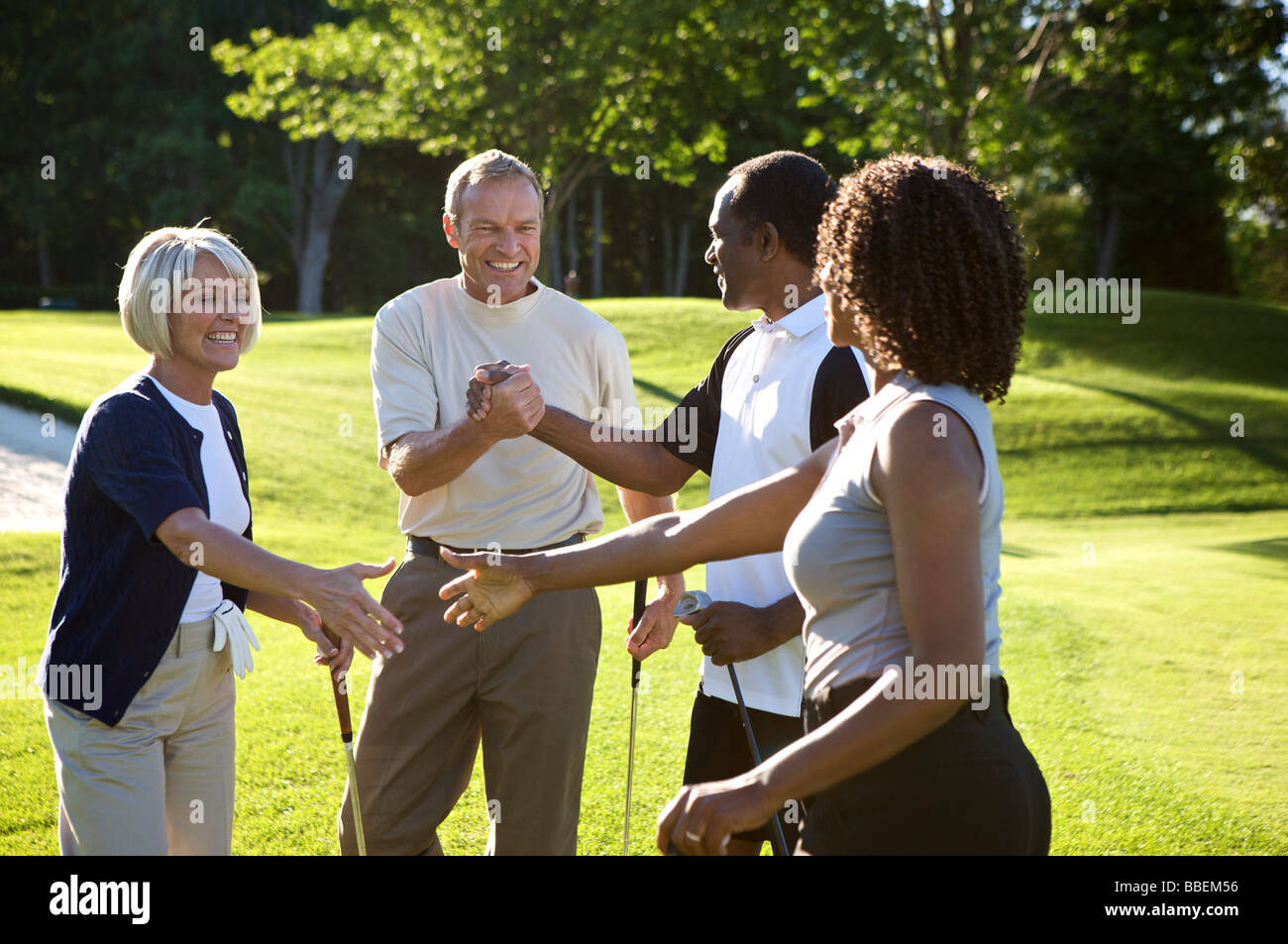 Couples Shaking Hands on Golf Course Stock Photo