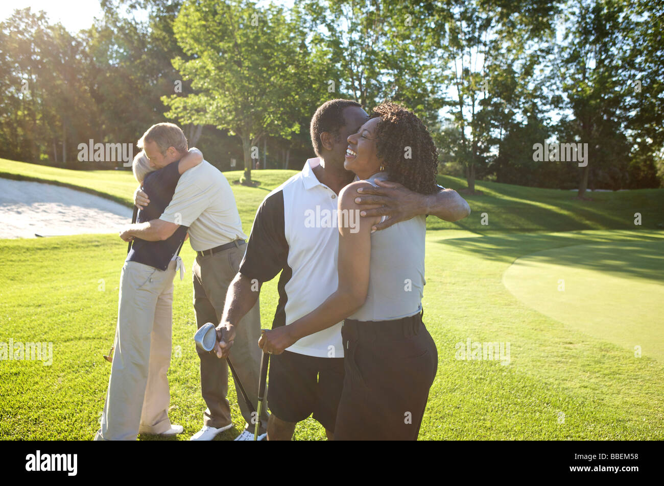 Couples Hugging on Golf Course Stock Photo