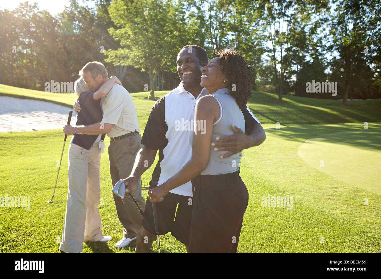 Couples Hugging on Golf Course Stock Photo