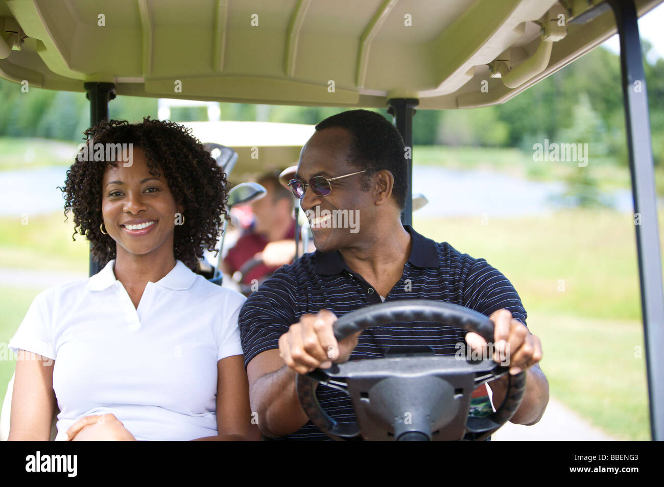 Portrait of Couple Riding in Golf Cart Stock Photo