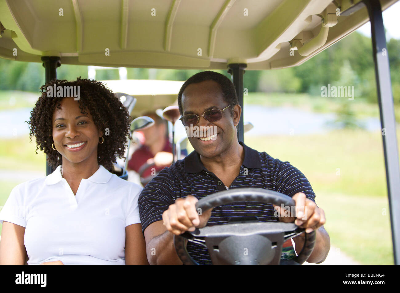 Portrait of Couple Riding in Golf Cart Stock Photo