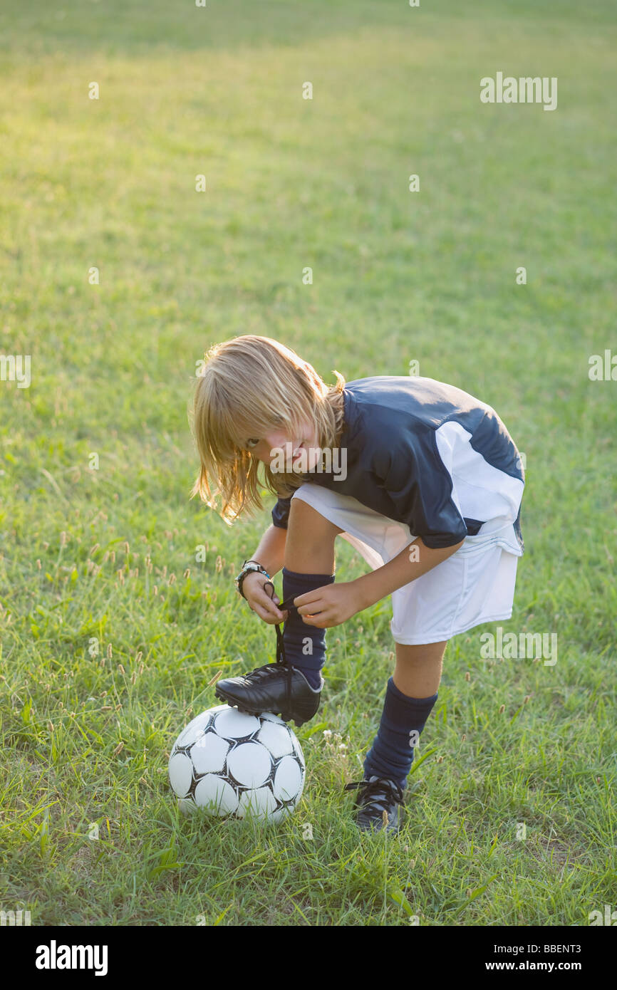 Soccer player tying laces on on football Stock Photo