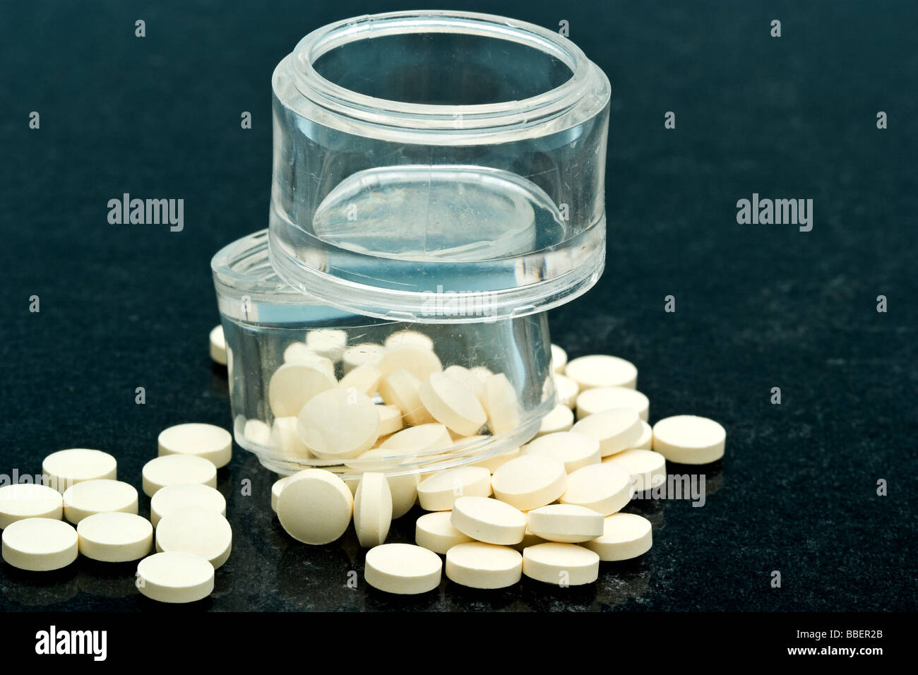 Two clear plastic vitamin containers overflowing with Folic acid vitamin pills Stock Photo