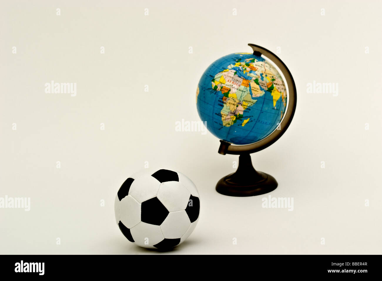 Soccer ball in front of a small globe of the world Stock Photo