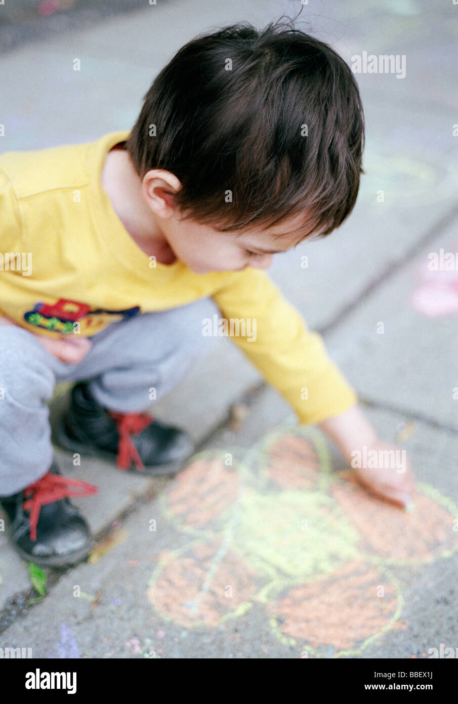 Two year old boy drawing with colorful chalk on a sidewalk Stock Photo ...
