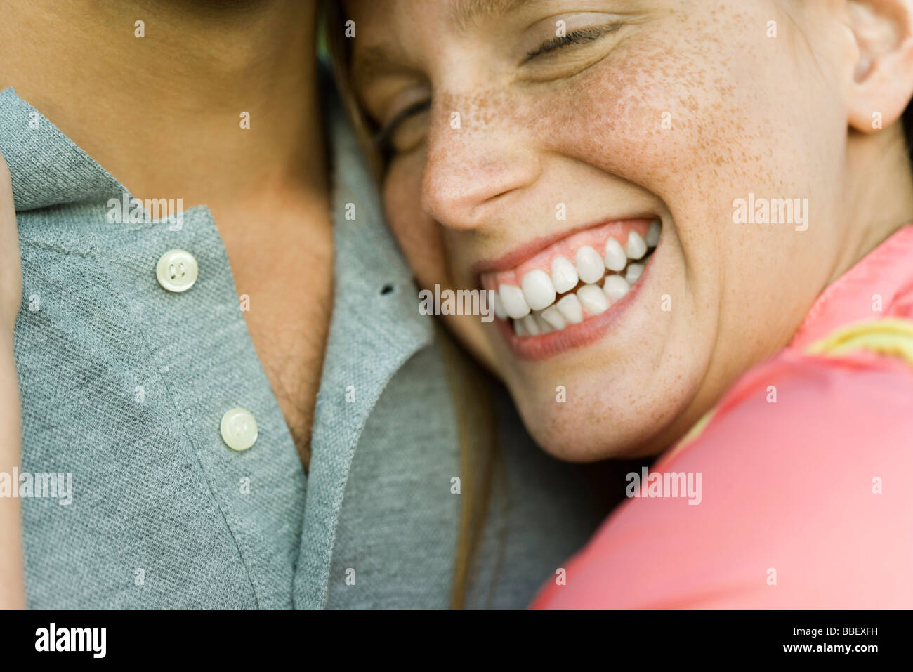 Young woman resting head on man’s chest, laughing, close-up Stock Photo