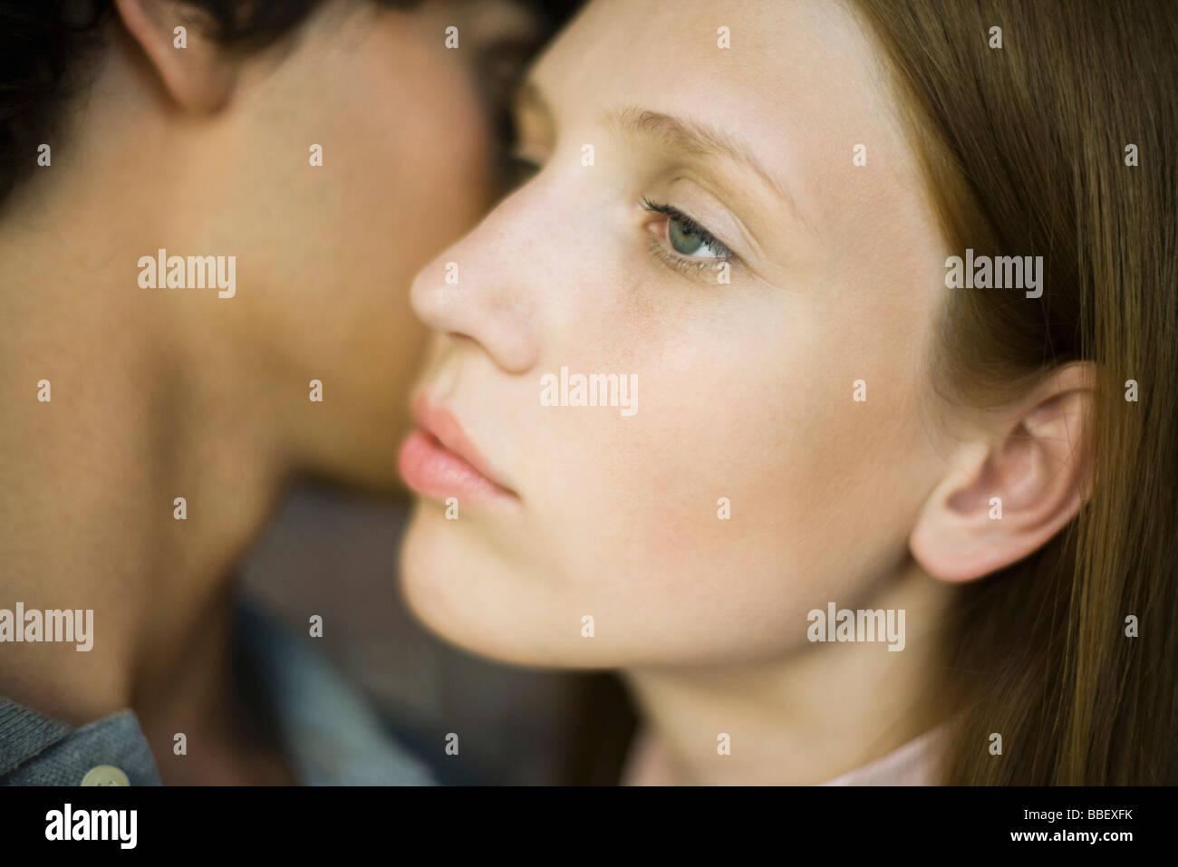 Young woman looking away distantly as man kisses her cheek Stock Photo