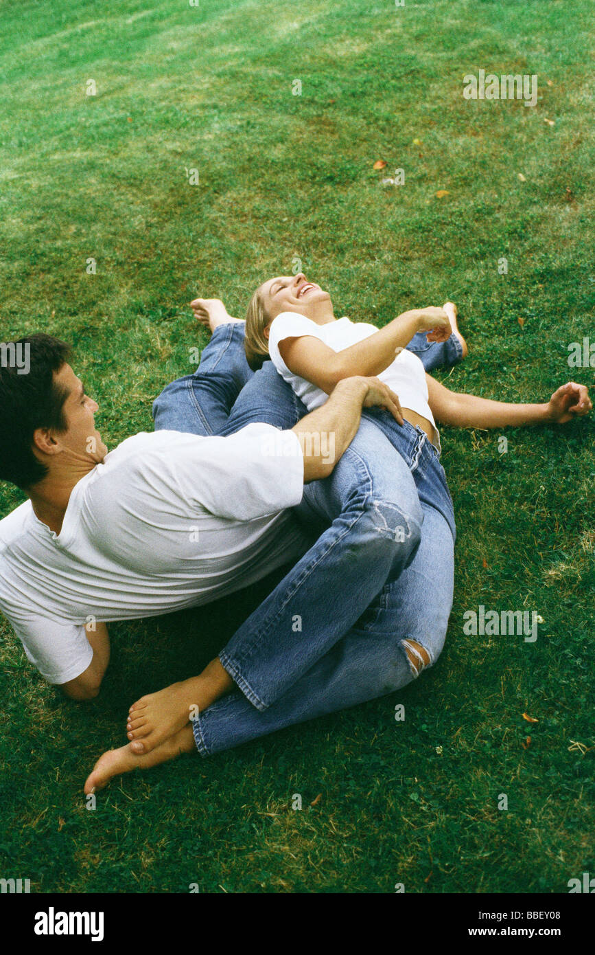 Couple reclining on ground together, laughing, high angle view Stock