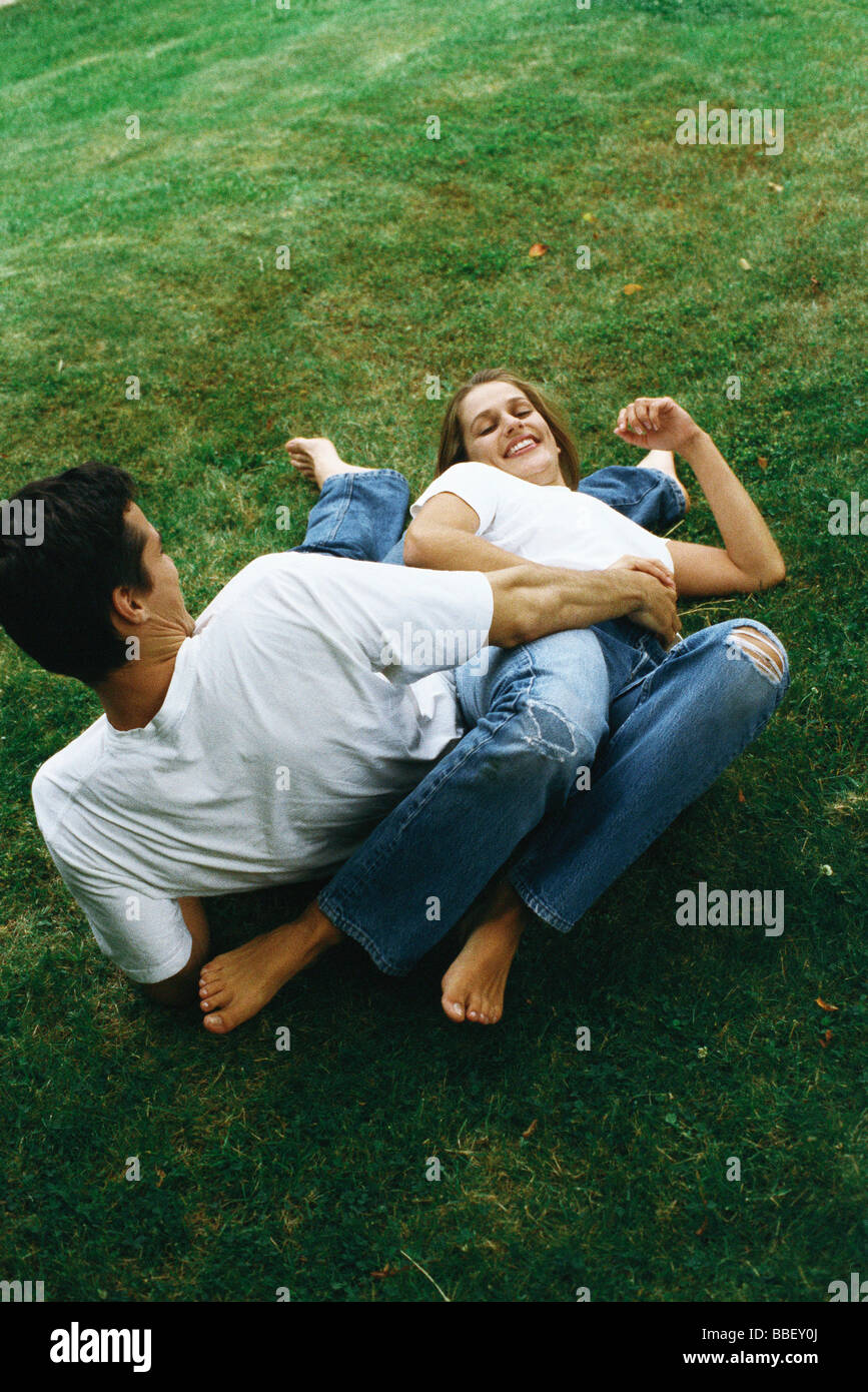 Couple reclining on ground together, laughing, high angle view Stock