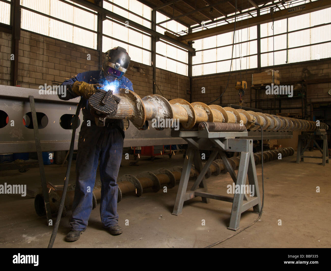 Man welding while refurbishing giant drill head inside industrial hall Lemmer the Netherlands Stock Photo