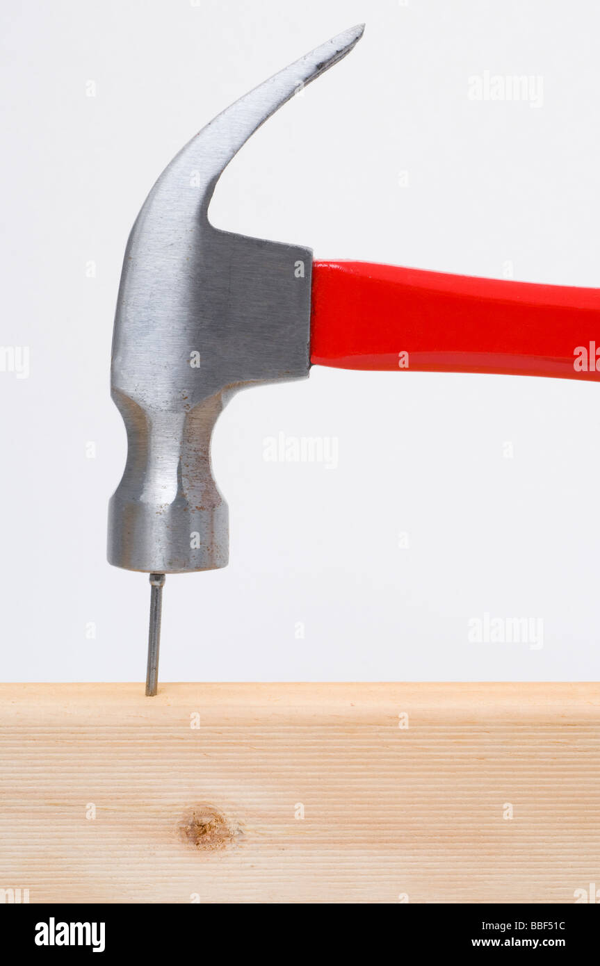 Hammer hitting a nail on the head into wood Stock Photo