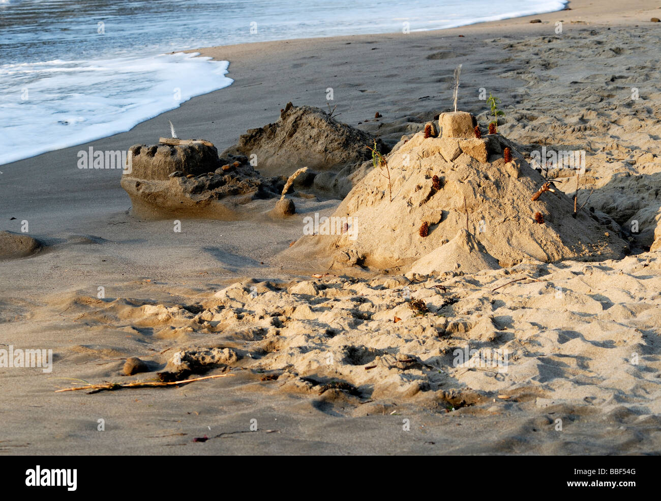 A child's sand castle about to be washed away by the incoming tide. Oregon USA Stock Photo