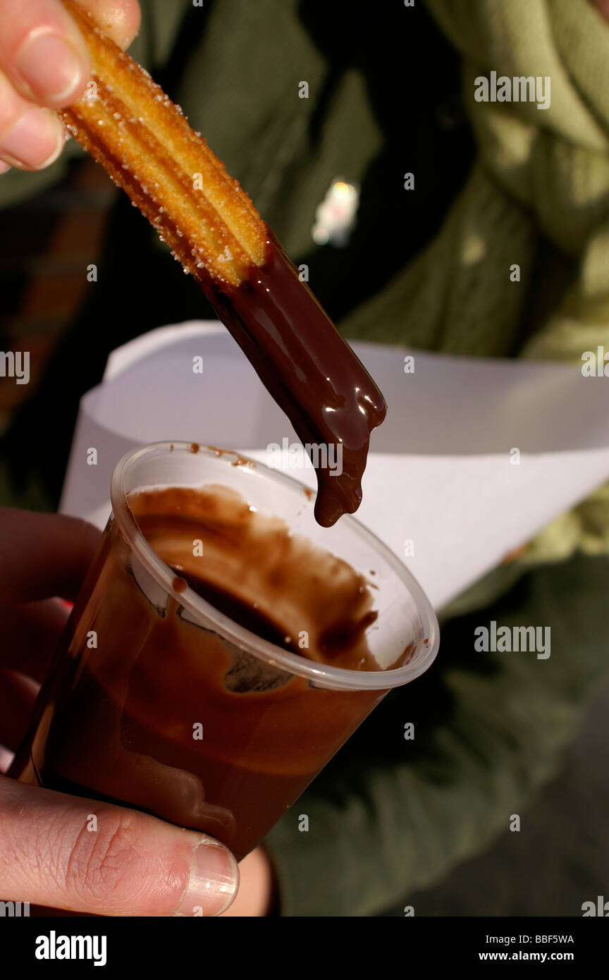 Dipping spanish donuts into chocolate. (Churros con chocolate Stock