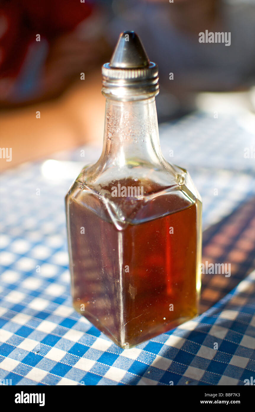 An old fashioned vinegar bottle stood on a blue and white gingham check table cloth in a