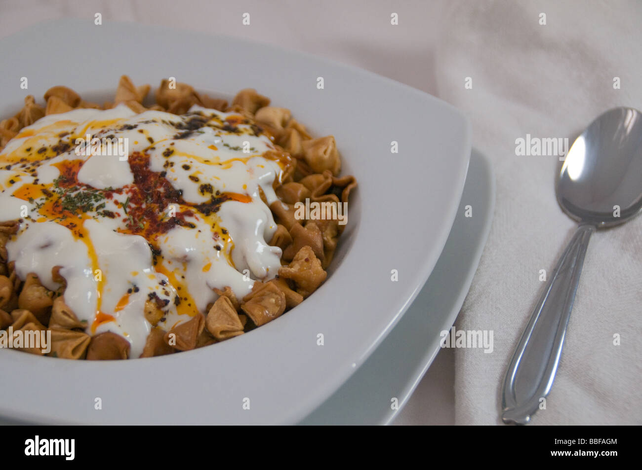 Turkish cuisine, manti (dumplings), fried and served with yogurt, mint and chilli peper Stock Photo