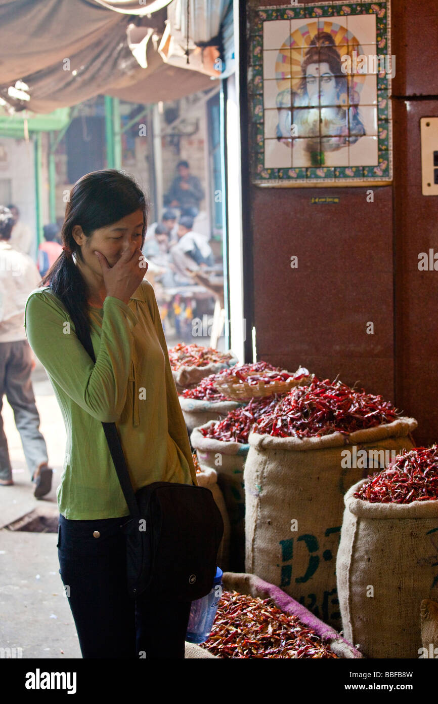 Chinese Tourist Holding her Nose because of Chili in the Spice Market in Delhi India Stock Photo