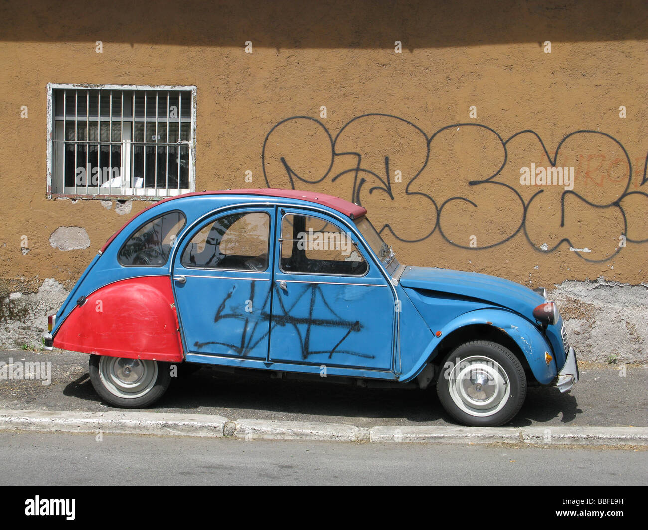 one citroen 2cv covered with graffiti in street in city town Stock Photo