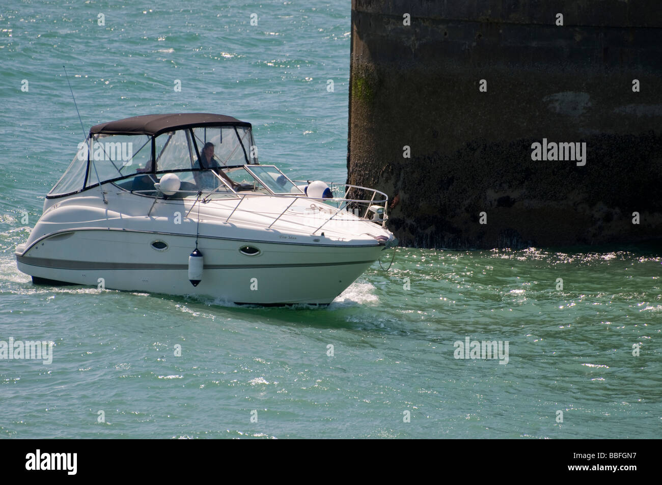 A motor cruiser passing close to a marine breakwater Stock Photo
