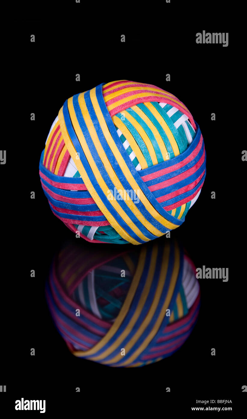 A ball of colorful rubber bands on a reflective black surface Stock Photo