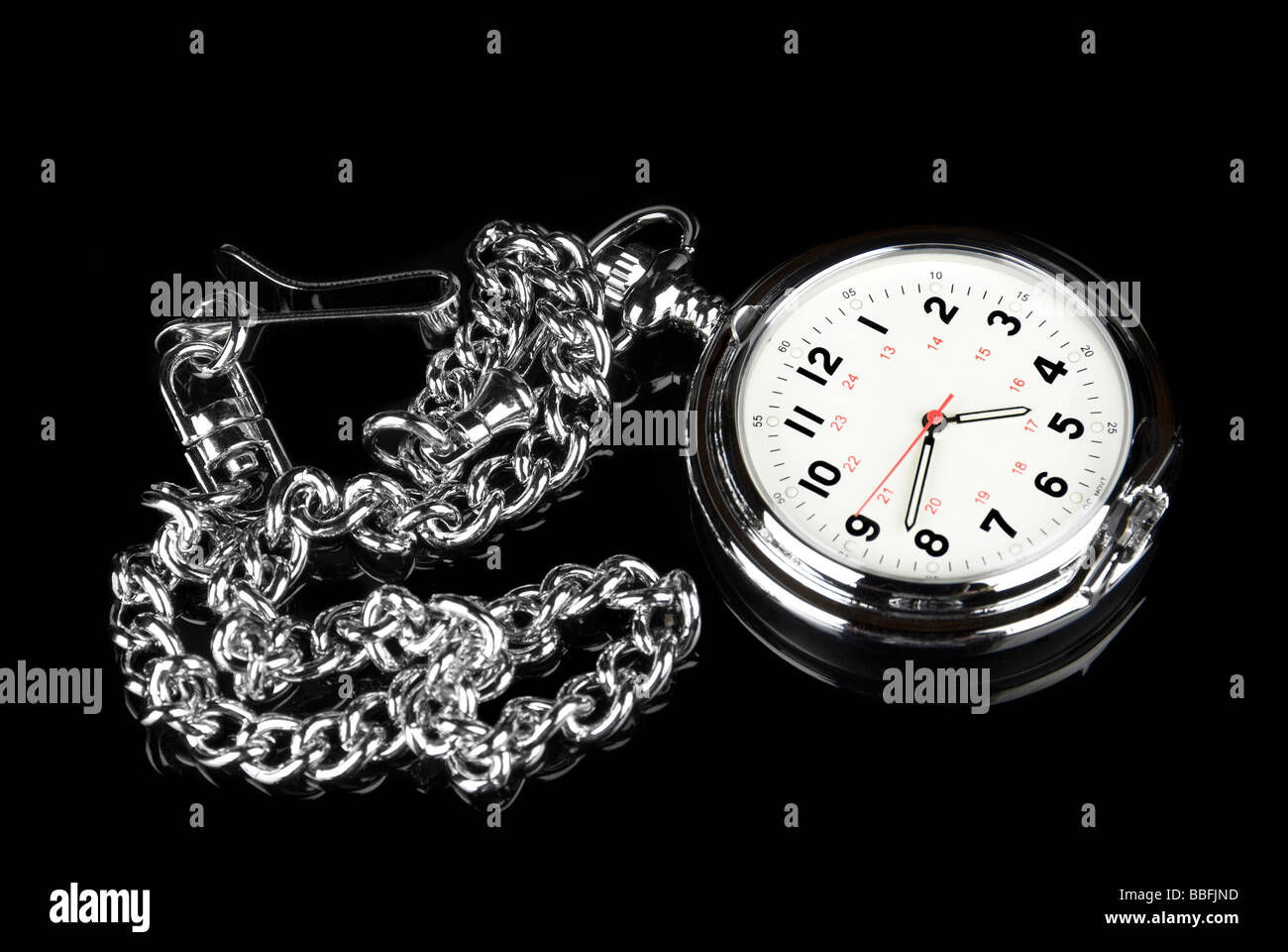 A pocket watch on a black reflective surface shows elegance and style Stock Photo