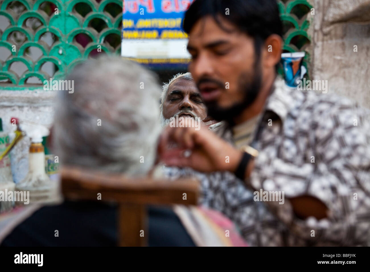 Barber Trimming a Muslim Man s Beard in Delhi India Stock Photo