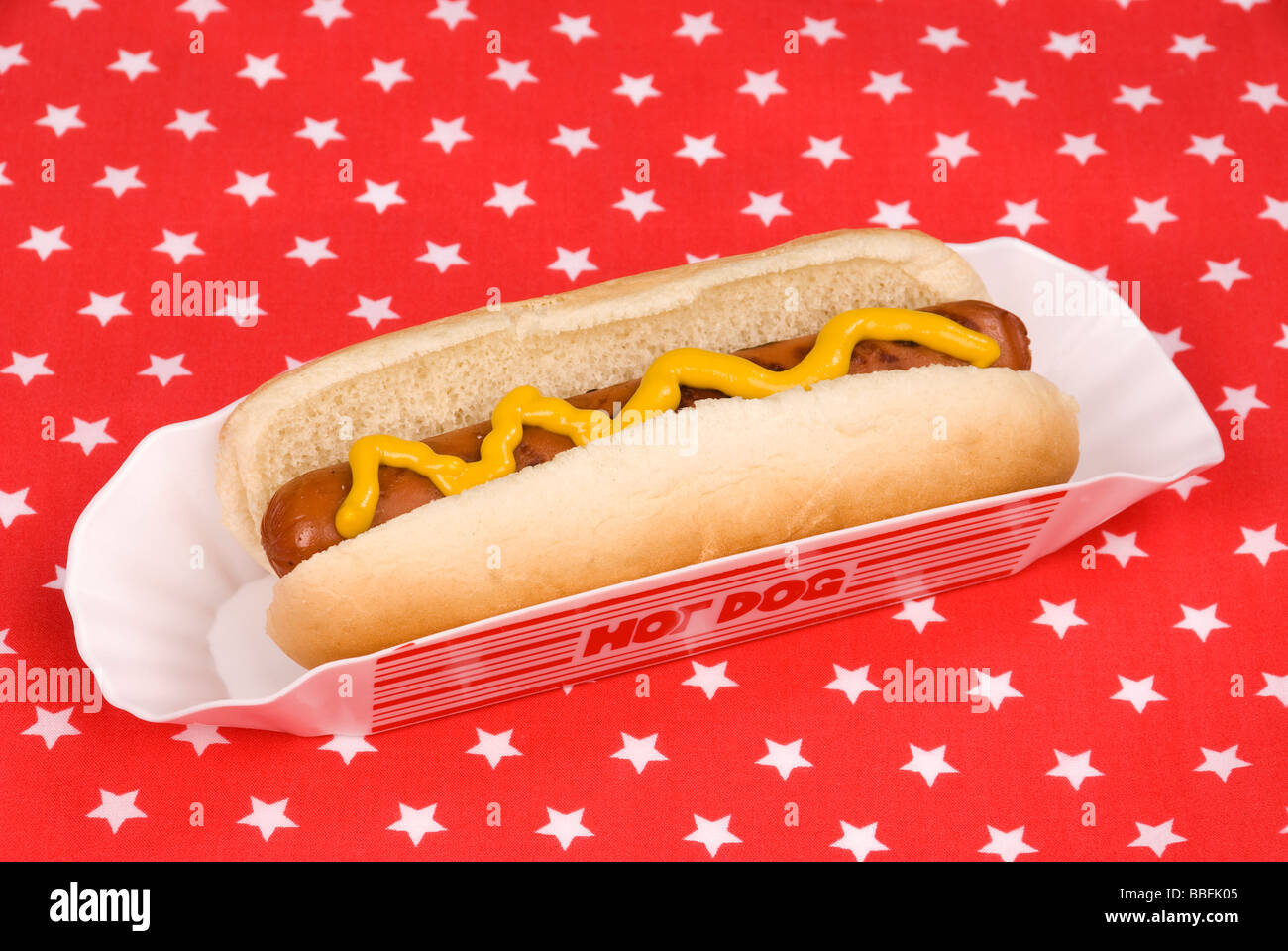A cooked hotdog with mustard on a patriotic tablecloth Stock Photo