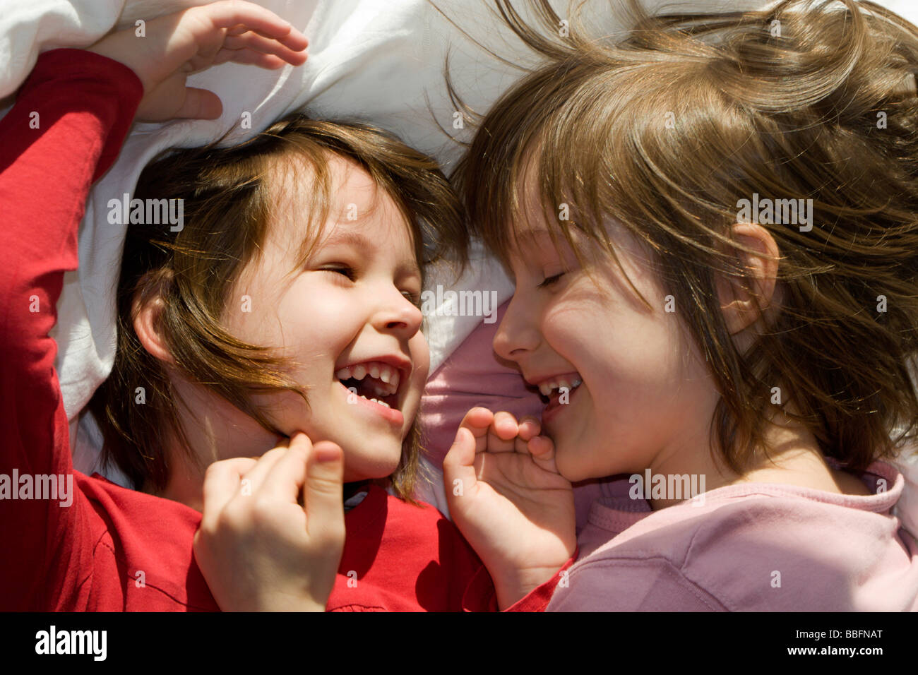 children - sisters by fun in the bed Stock Photo