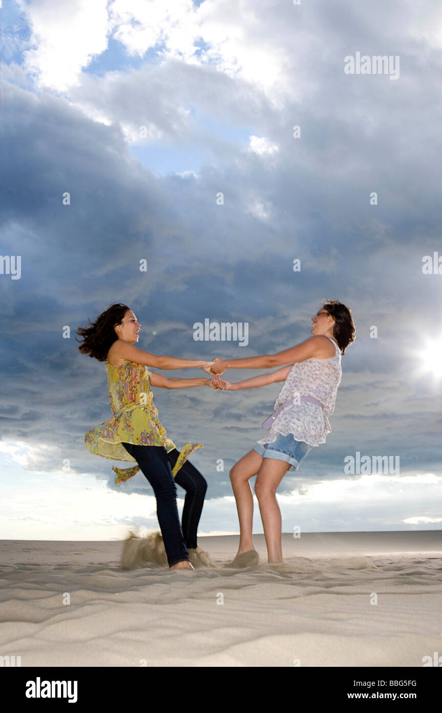 Girlfriends twirl in sand Stock Photo