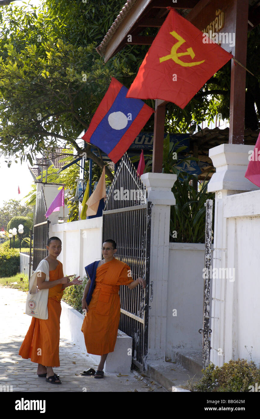 Buddhist monks in central Vientiane, Laos, with communist flag and Lao flag Stock Photo