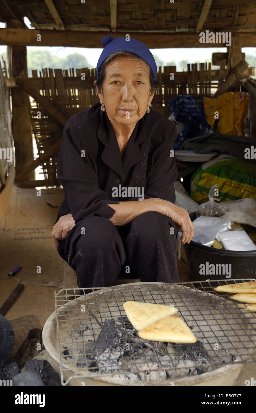 Laotian old woman grilling bread in her hut of the ethnic minority