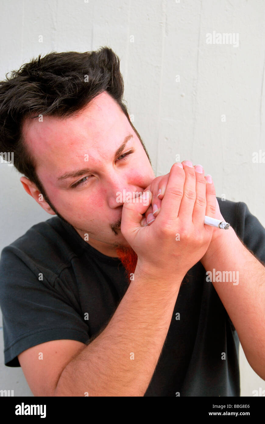 Drugs, young man smoking a joint, hand-rolled cigarette Stock Photo