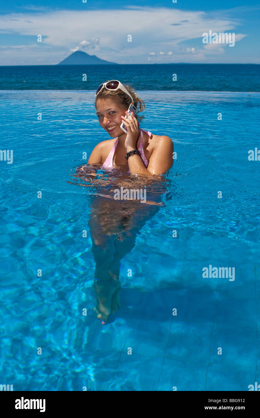 Woman with mobile phone in the pool, Indonesia, Southeast Asia Stock Photo