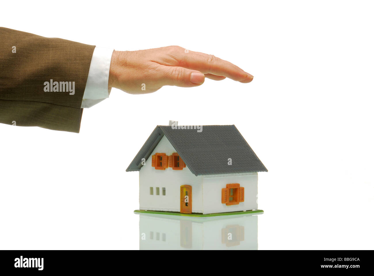 Business man holding hand over model house, symbolic of protection Stock Photo