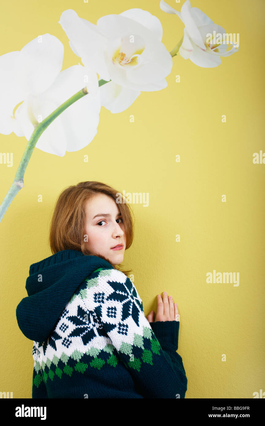 Young girl standing in front of a wallpaper with flower Stock Photo