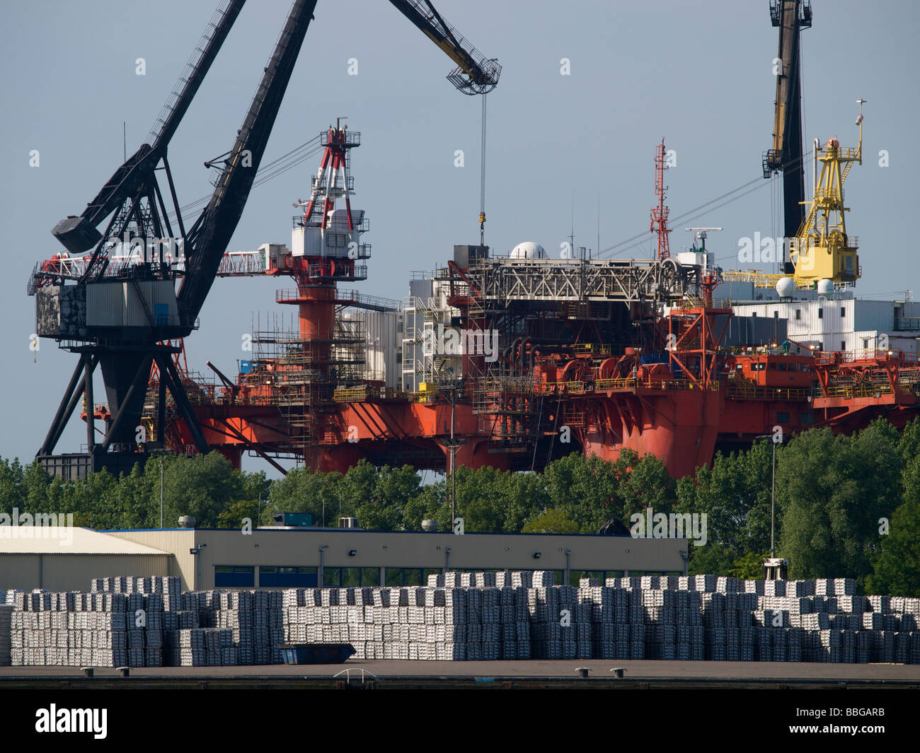 Oil production platform being renovated in the port of Rotterdam with large quantity of aluminium in front Stock Photo
