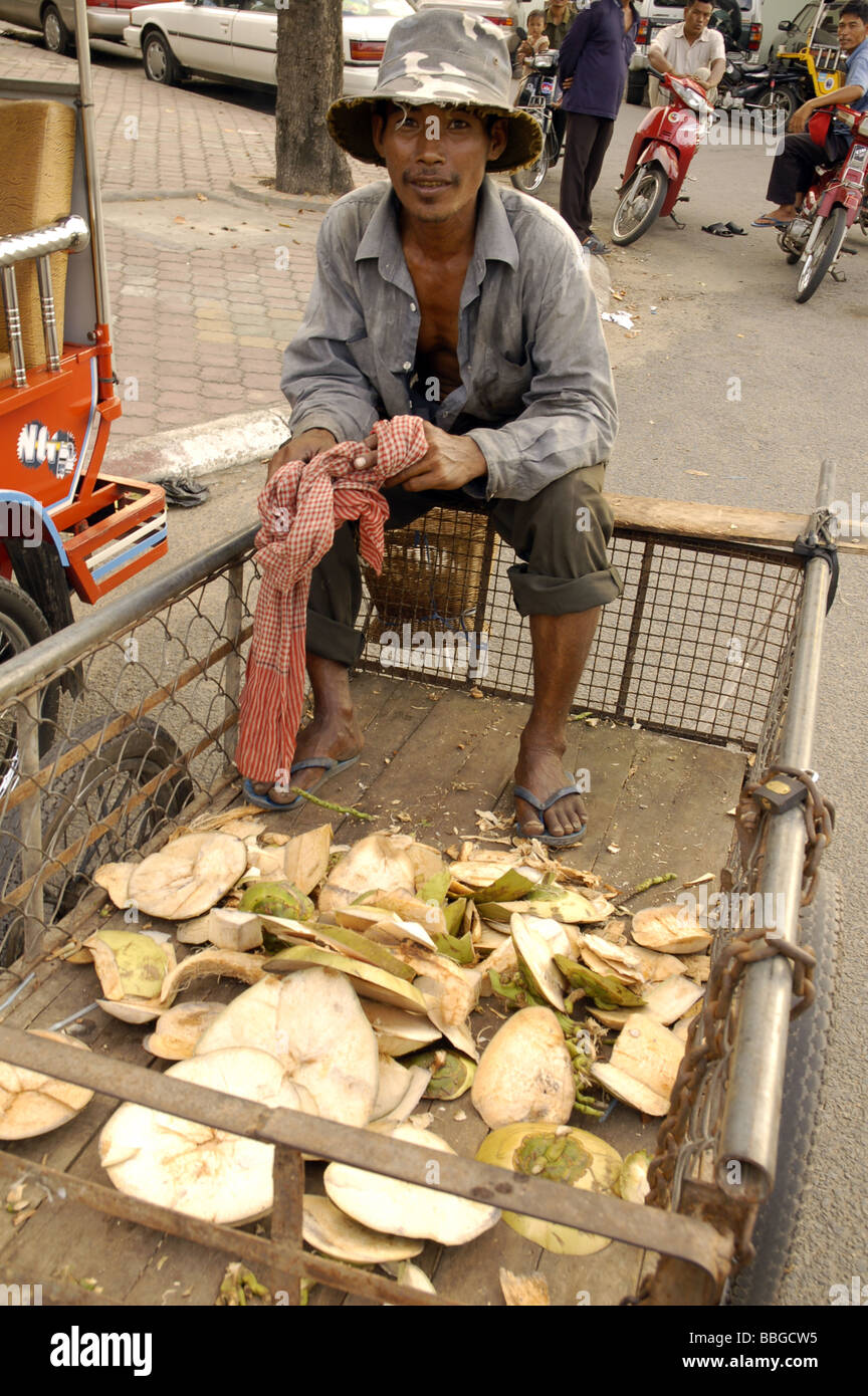 Cambodian man peeling young coconuts in his cart in central Phnom Penh, Cambodia Stock Photo