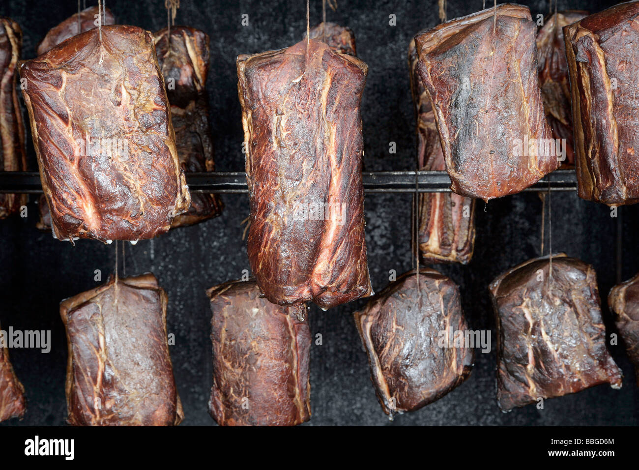 Smoked pork joints in a smoker, production of the bavarian specialty Schwarzgeraeuchertes, smoked ham in a butchery in Hengersb Stock Photo
