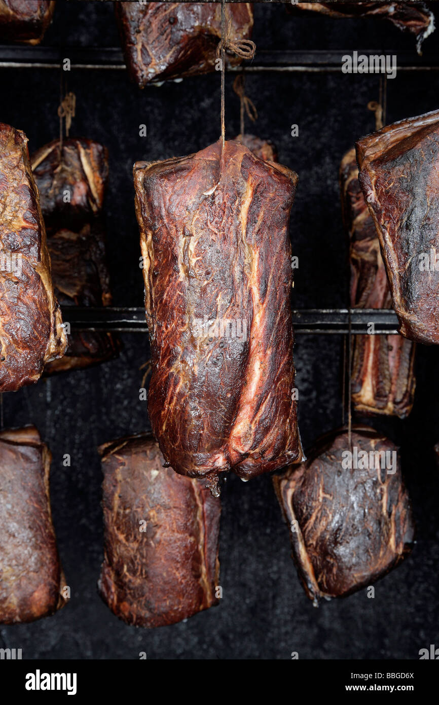Smoked pork joints in a smoker, production of the bavarian specialty Schwarzgeraeuchertes, smoked ham in a butchery in Hengersb Stock Photo