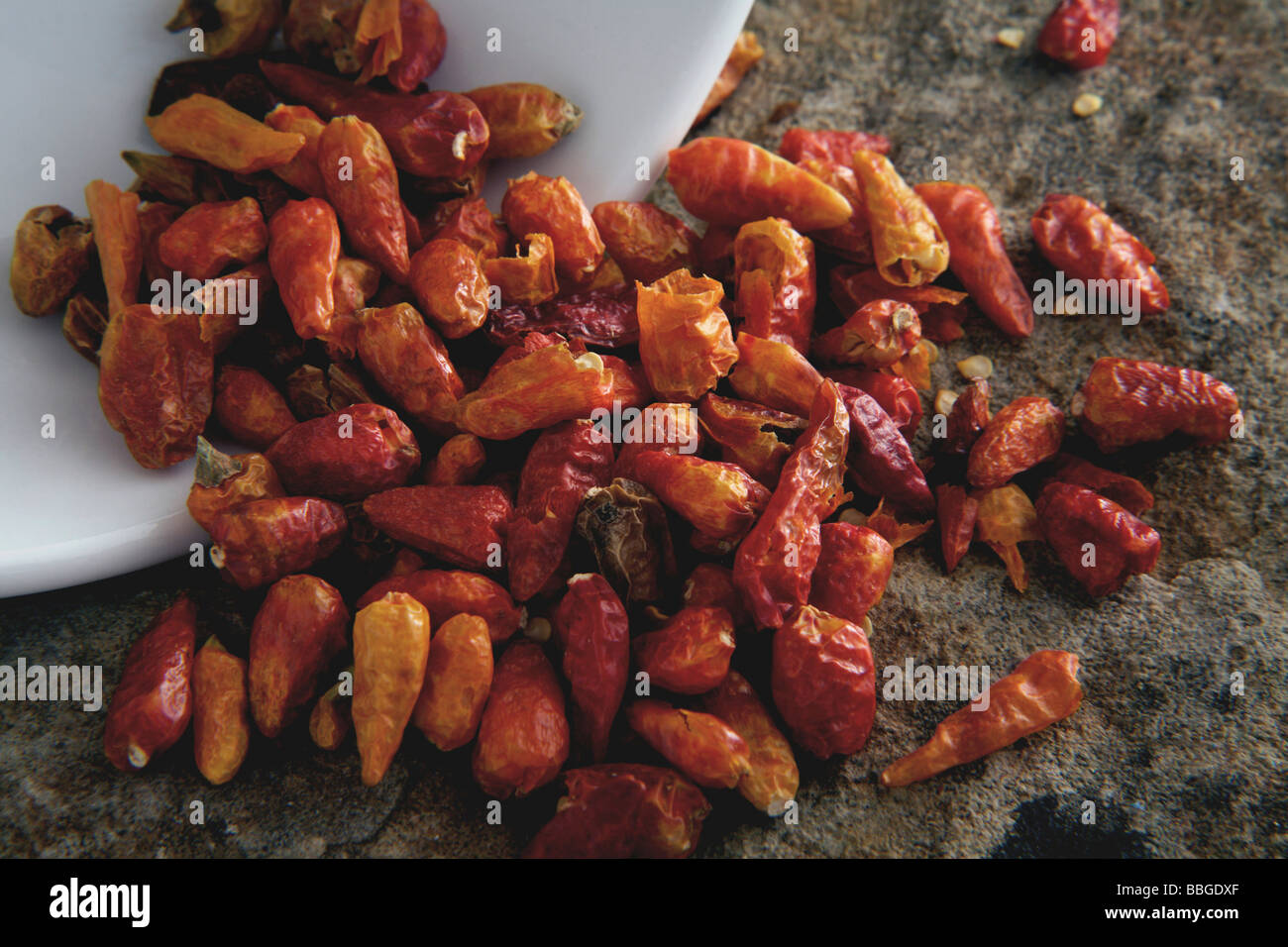 Dried chili peppers tipped from a bowl Stock Photo