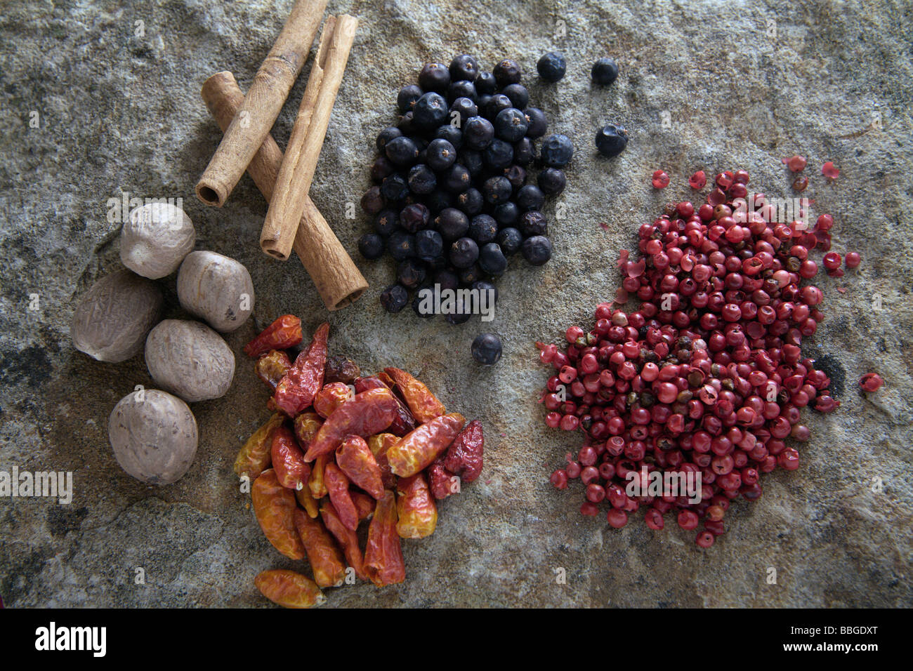 Different spices on a stone slab, juniper, chili peppers, red pepper,  nutmeg, cinnamon sticks Stock Photo - Alamy