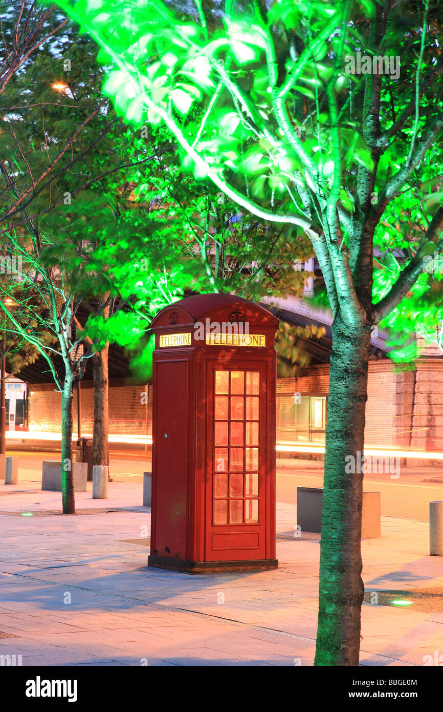 Red telehone box at night with green lit trees London England Stock Photo