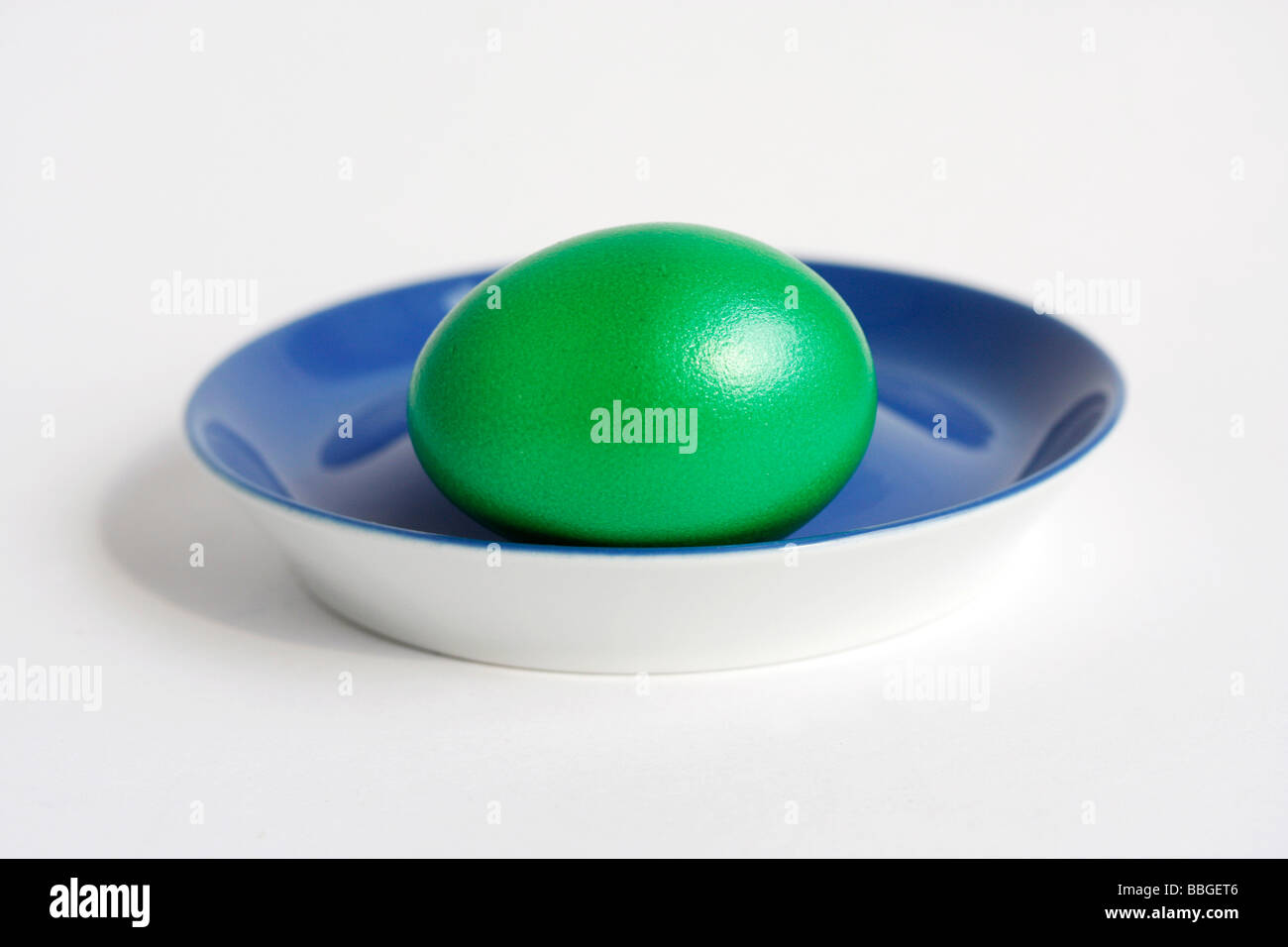 Green dyed egg on an egg cup, Easter Stock Photo